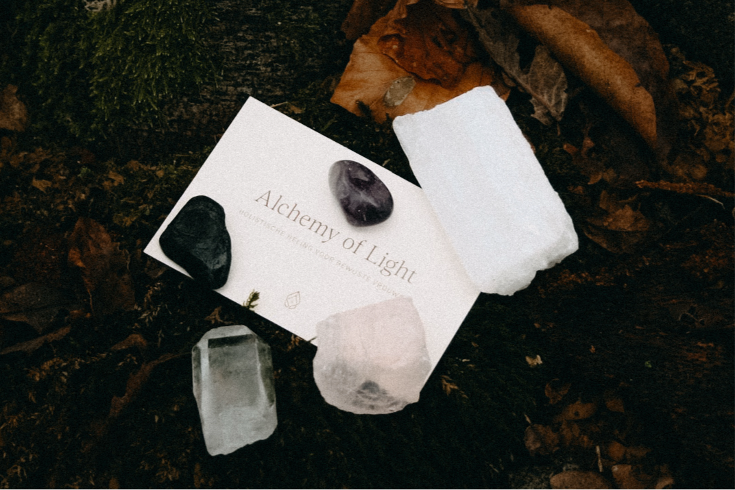 Edelstenensetje met vijf kristallen in wit linnen zakje op boomstronk – rozenkwarts, amethist, seleniet, toermalijn en bergkristal.