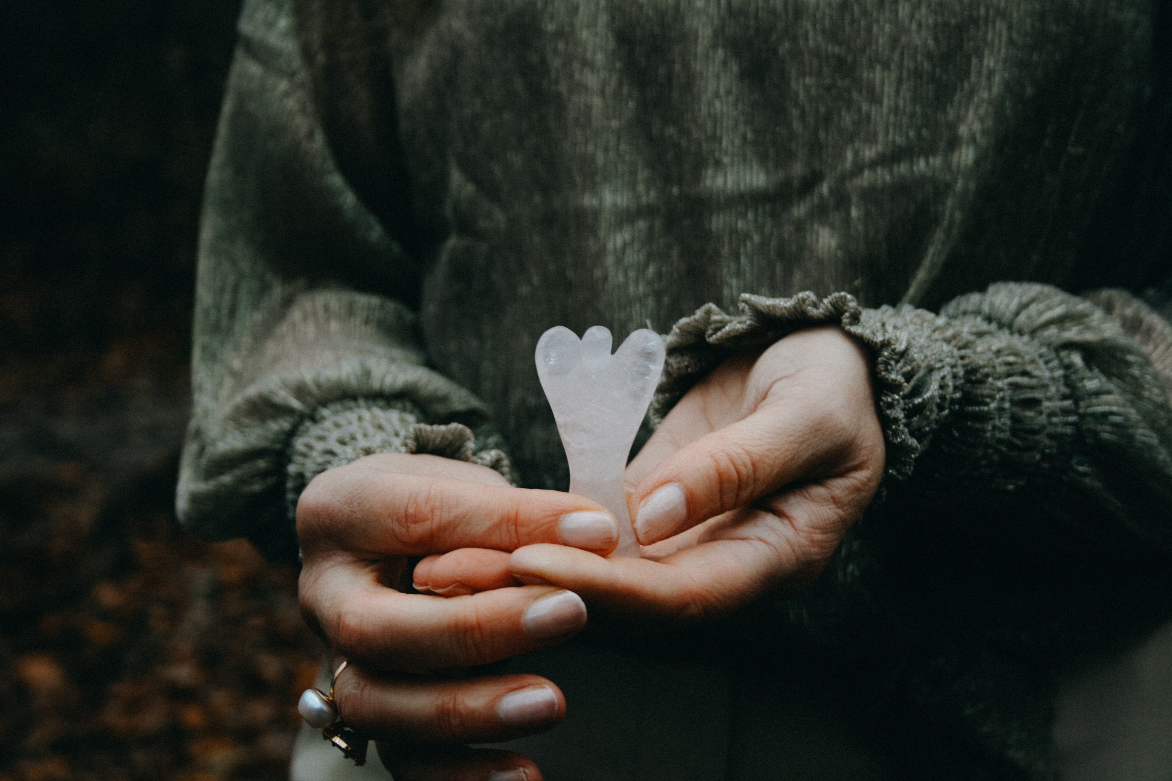 Rozenkwarts engeltje vastgehouden door twee vrouwen handen.