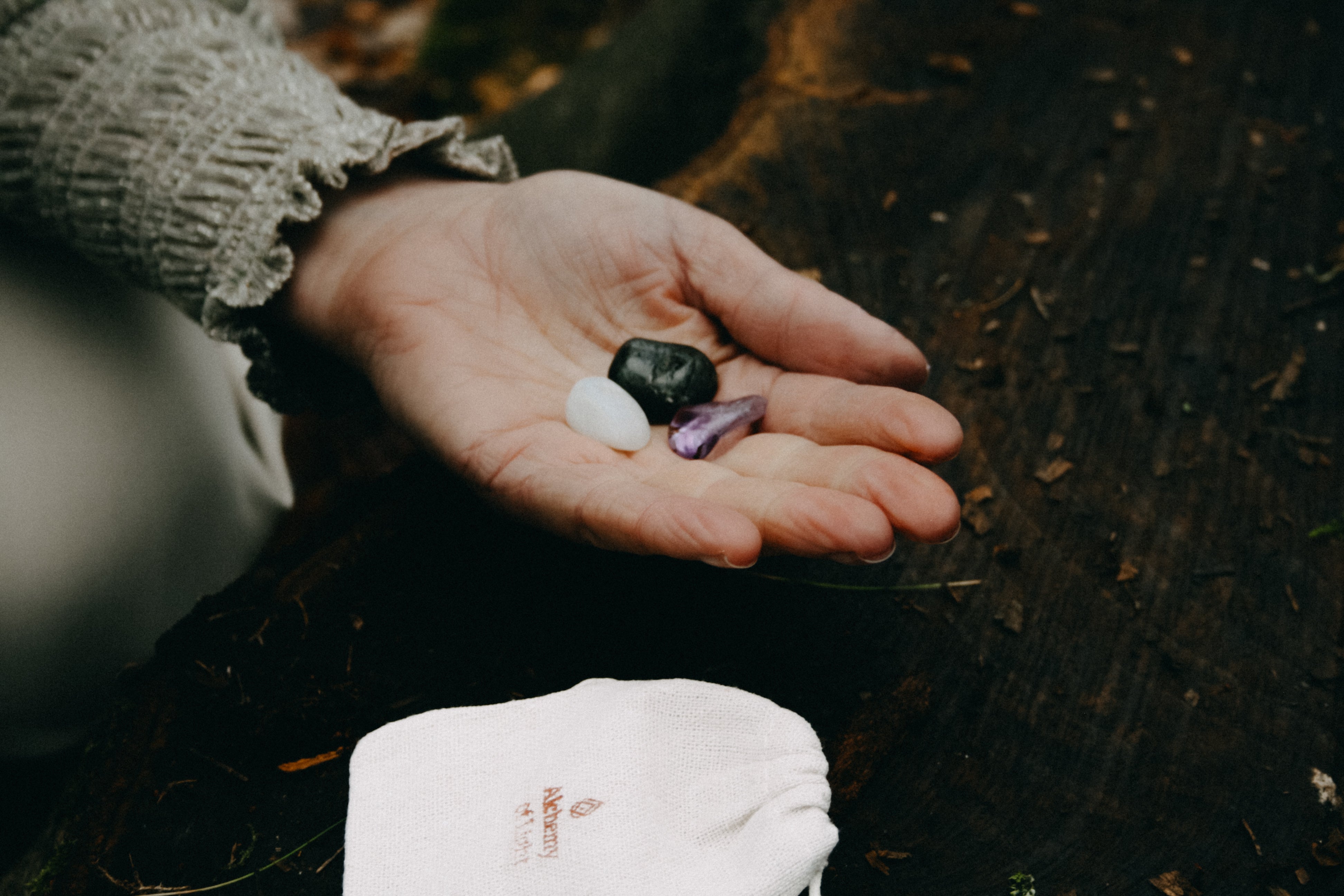 Hand met edelstenen labradoriet, amethist en maansteen – spirituele stenen voor spirituele ontwikkeling en intuïtie.