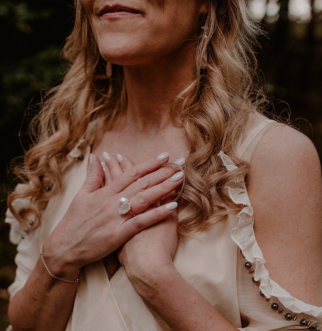 Vrouw met gesloten ogen en handen op haar hart tijdens een cacao ceremonie in de natuur. Een moment van verbinding en zelfliefde.